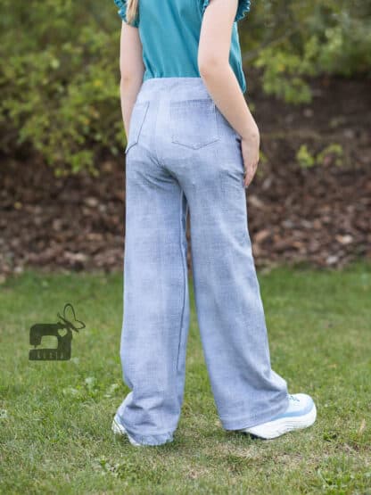 Schnittmuster Wide Legs: hellblaue Wide-Leg-Hose in Jeansoptik mit Po-Taschen, von hinten auf der Wiese.