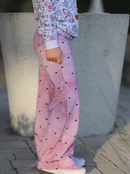 Schnittmuster Wide Legs: rosa Baggy Hose mit kleinen Herzen, seitlich vor einem Betonkübel.