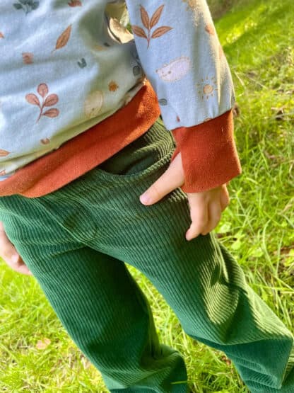 Grüne Baggy Hose aus Cordjersey mit Blätter-Shirt im Gras, genäht nach dem Schnittmuster Wide Legs.