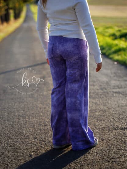 Dunkellila Wide-Leg-Hose in Jeansoptik von hinten auf einer Straße im Abendlicht.