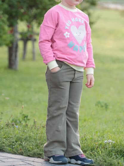 Khakifarbene selbst genähte weite Jogginghose mit rosa Sweater auf einer Wiese.