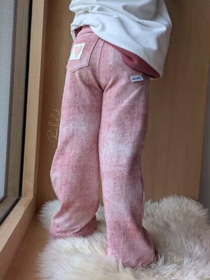 Rosa Baggy Hose in Jeansoptik mit Po-Tasche auf einem Lammfell, genäht nach dem Schnittmuster Wide Legs.
