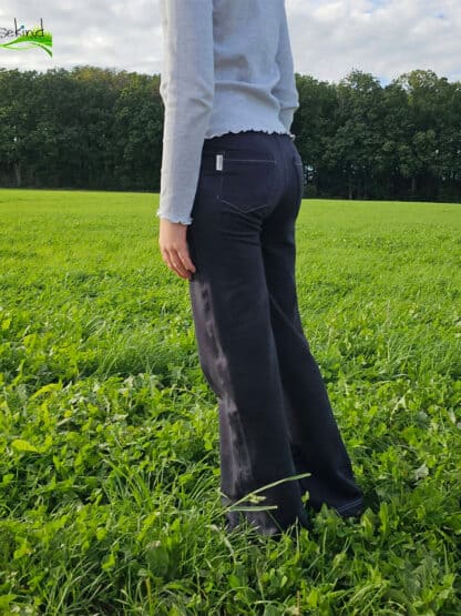 Schwarze selbst genähte Wide-Leg-Hose, seitlich auf einer weiten grünen Wiese.