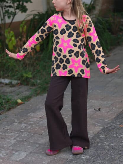Schnittmuster Wide Legs: dunkelbraune weite Hose mit pinkem Sternen-Shirt und ausgestreckten Armen.