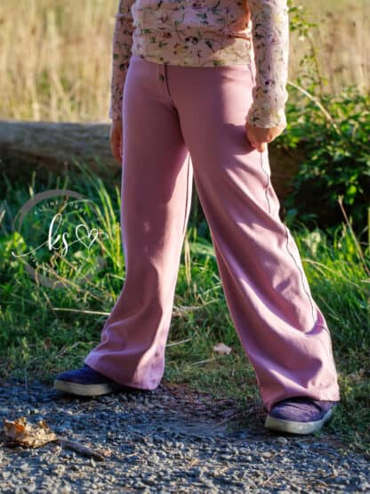 Altrosa Wide-Leg-Hose mit gemustertem Shirt im Gehen auf einem Schotterweg.