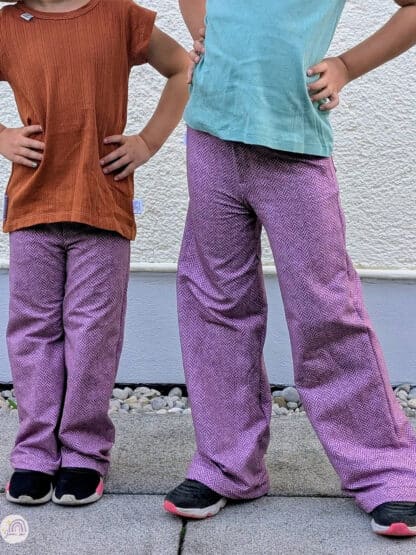 Schnittmuster Wide Legs: zwei Kinder in lila Baggy Hosen vor einer weißen Hauswand.