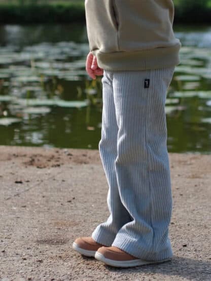 Hellblaue selbst genähte Wide-Leg-Hose aus Cord am Ufer eines Teichs.