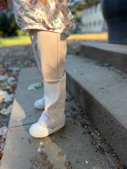 Beige Baggy Hose auf grauen Betonstufen im Freien, dazu weiße Sneaker.