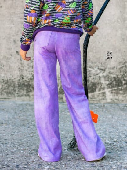 Schnittmuster Wide Legs: lila Baggy Hose in Jeansoptik mit Po-Taschen, daneben ein Hexenbesen.