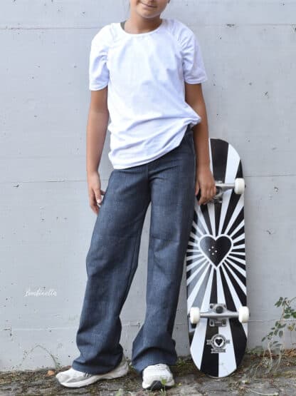 Dunkle selbst genähte Baggy Hose in Jeansoptik mit weißem T-Shirt, daneben ein Skateboard.